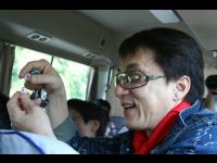 In the van on the way to the hotel, Jackie shows off his mobile phone strap.