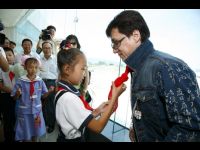At the airport in Guiyang, a young girl ties the symbol of a Chinese student - a red bandana - around Jackie's neck.