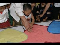 Jackie lends a hand to one of the students as he puts his handprints in the clay.