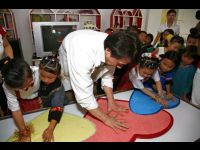 Jackie and the children place their handprints in clay hearts.
