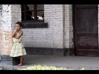 A young resident of Guiyang watches all the excitement from her doorway.