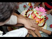 Everyone lends a hand to cut the birthday cake.