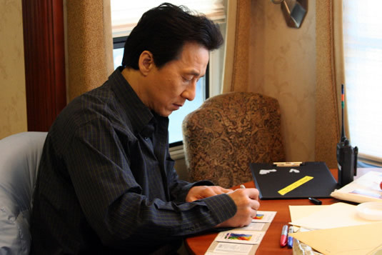 During a quiet moment in his trailer, Jackie signs autographs for chairty.